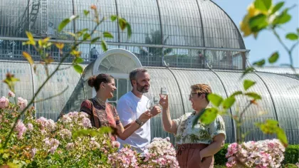 Three people enjoying a glass of wine in the Rose Garden at Kew