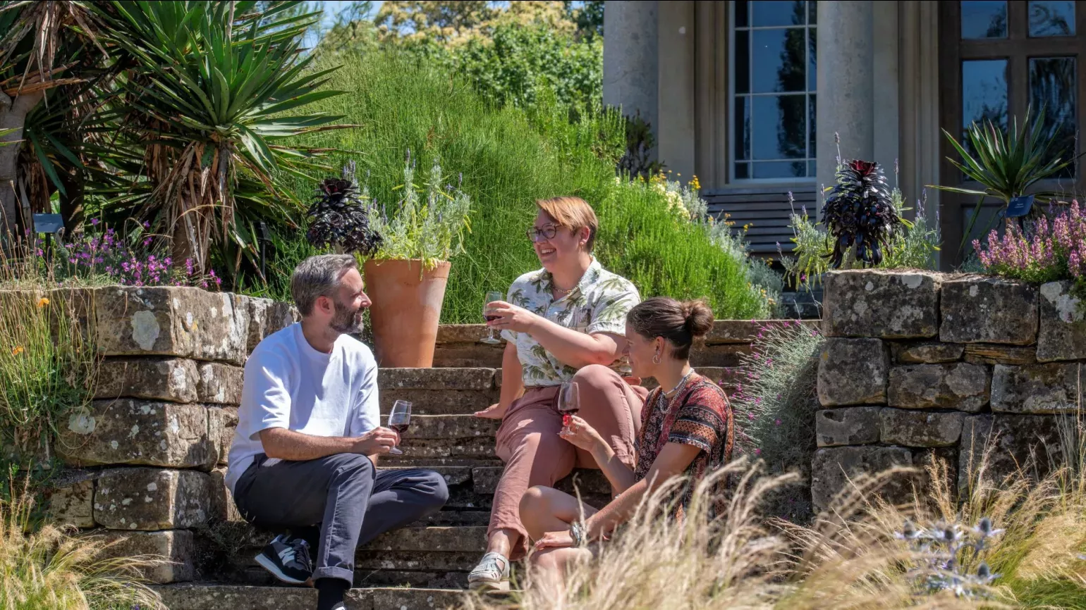 Three people enjoying a glass of wine in the Mediterranean Garden at Kew