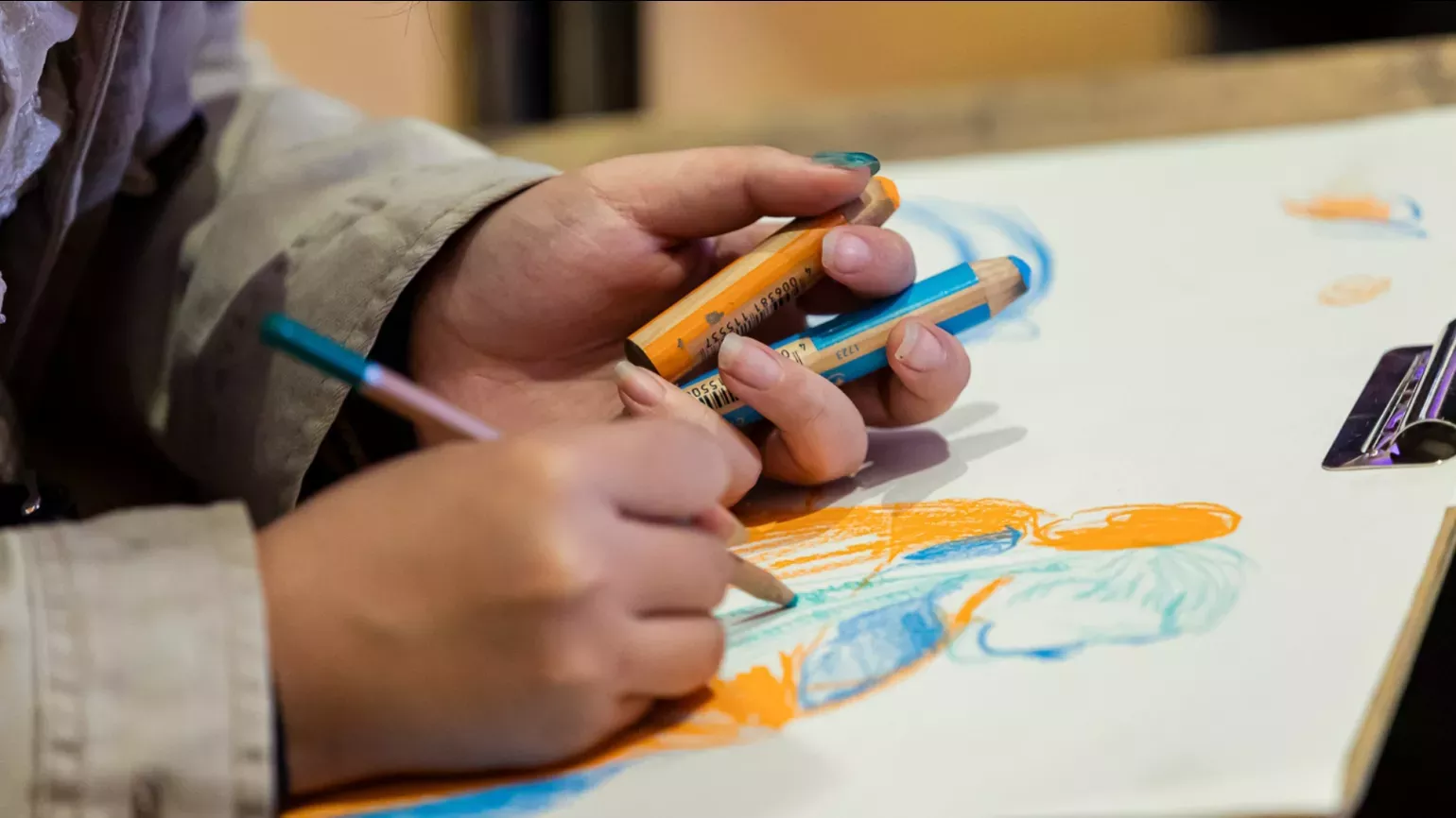 Hands drawing with pencils