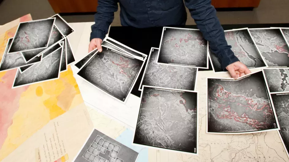 Researcher with table full of map print outs