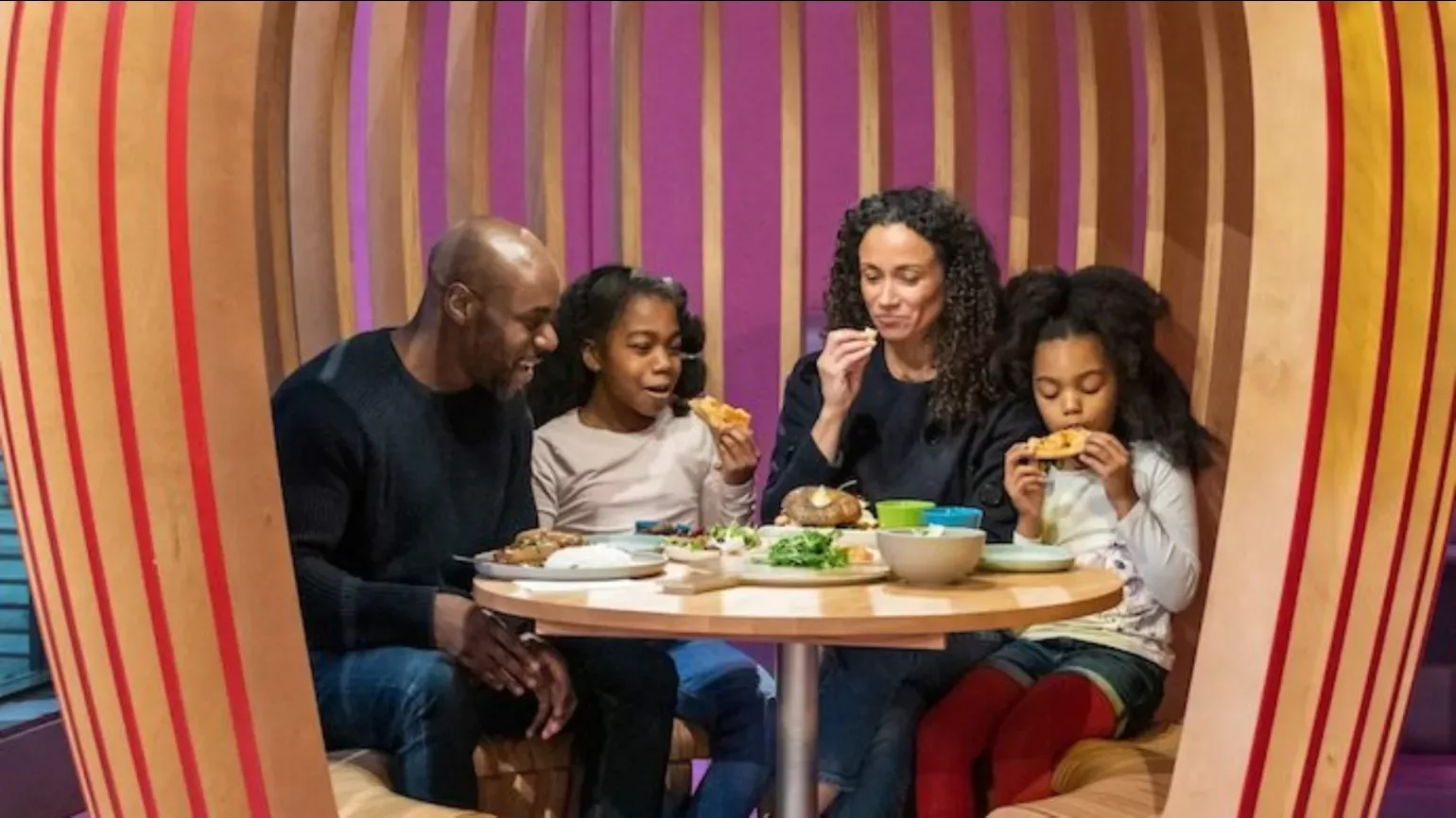 A family eat a meal at a colourful restaurant booth