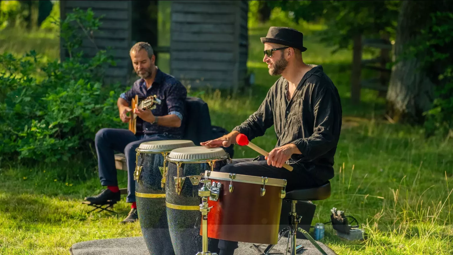 A pair of people playing music in a woodland