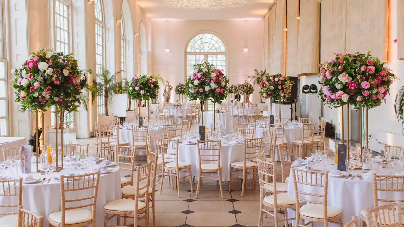 Round tables, large flower arrangements and wooden chairs at a wedding at Kew