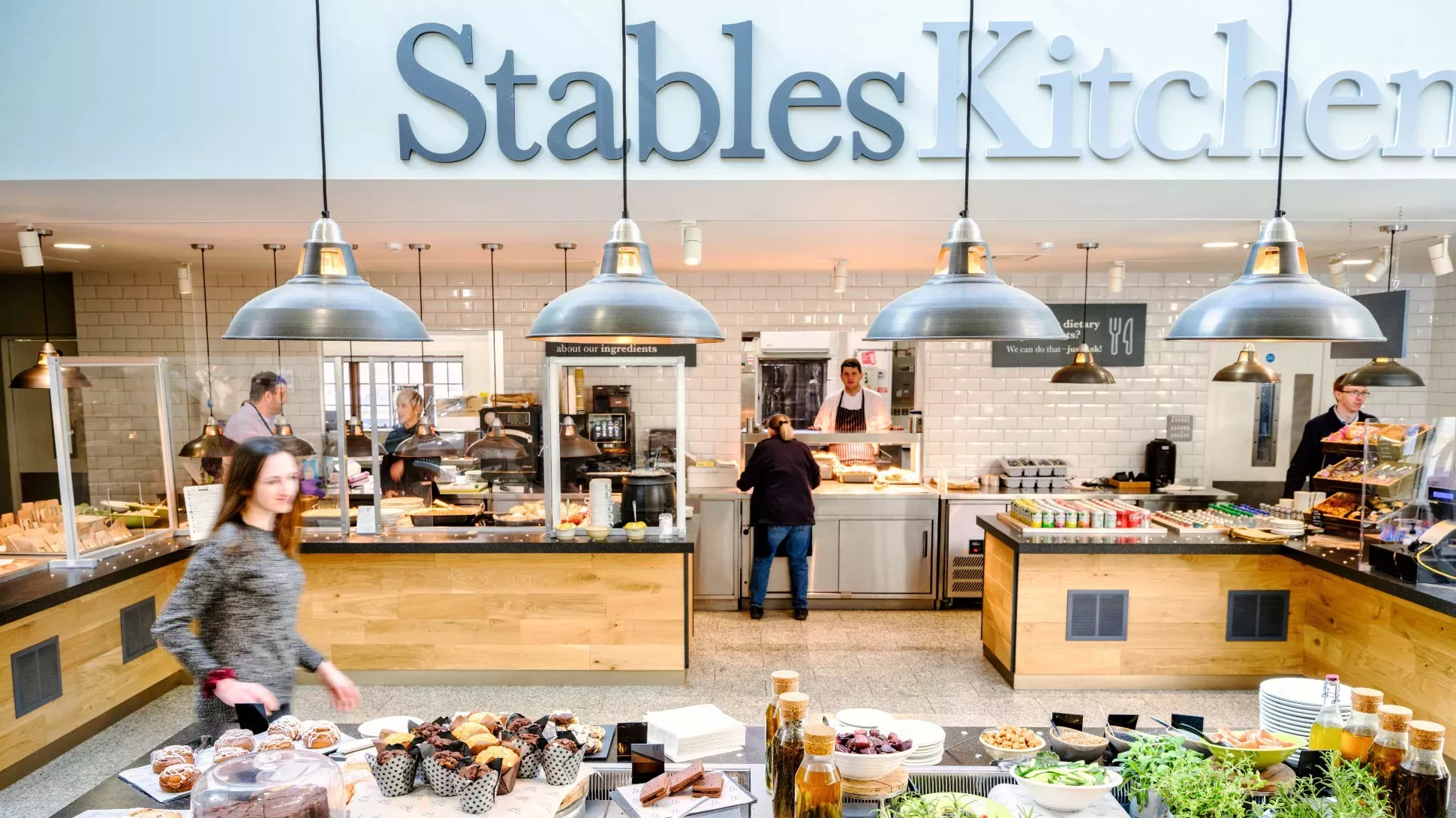 A restaurant kitchen with people and a wide range of food