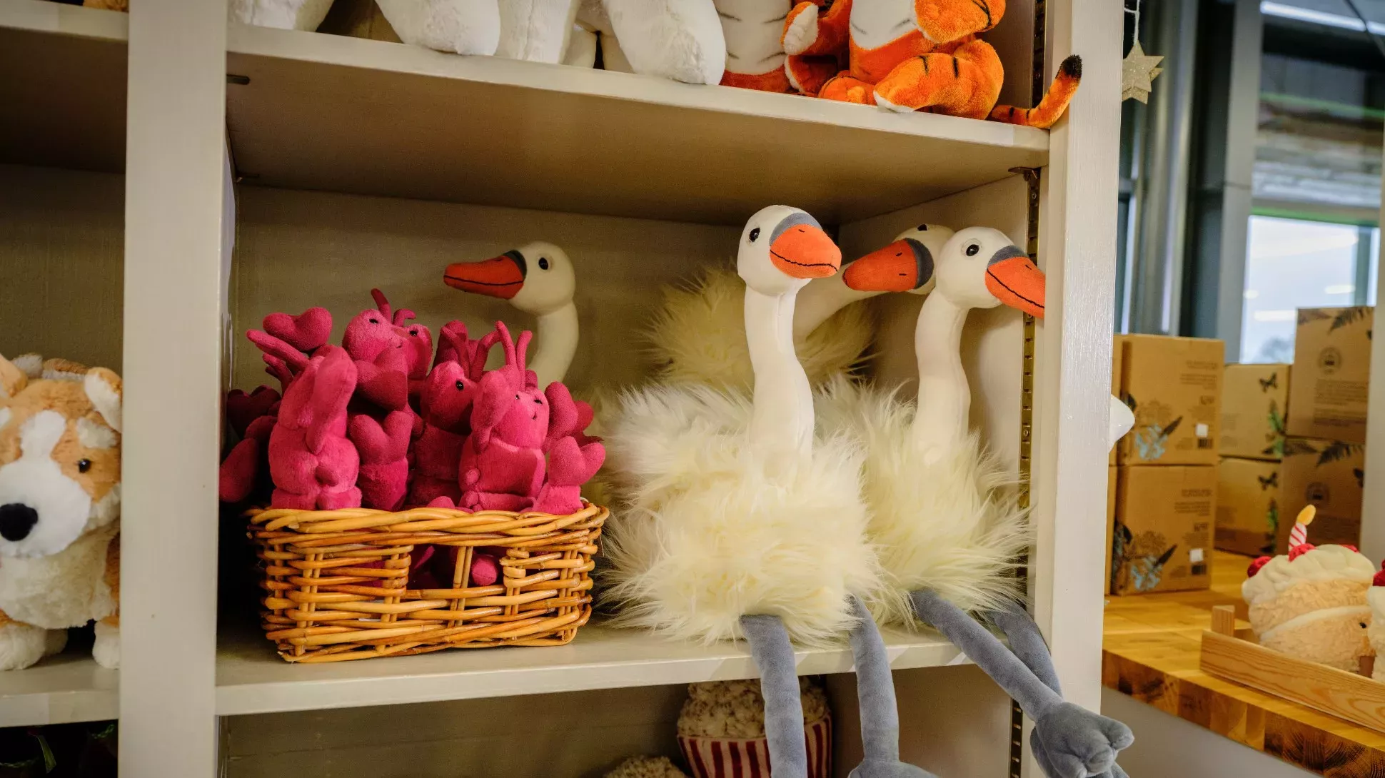 A collection of stuffed animals, including swans on a shop shelf