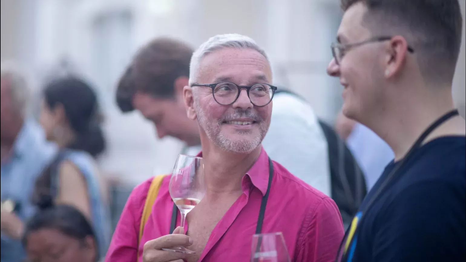 Two men chatting and holding glasses of white wine