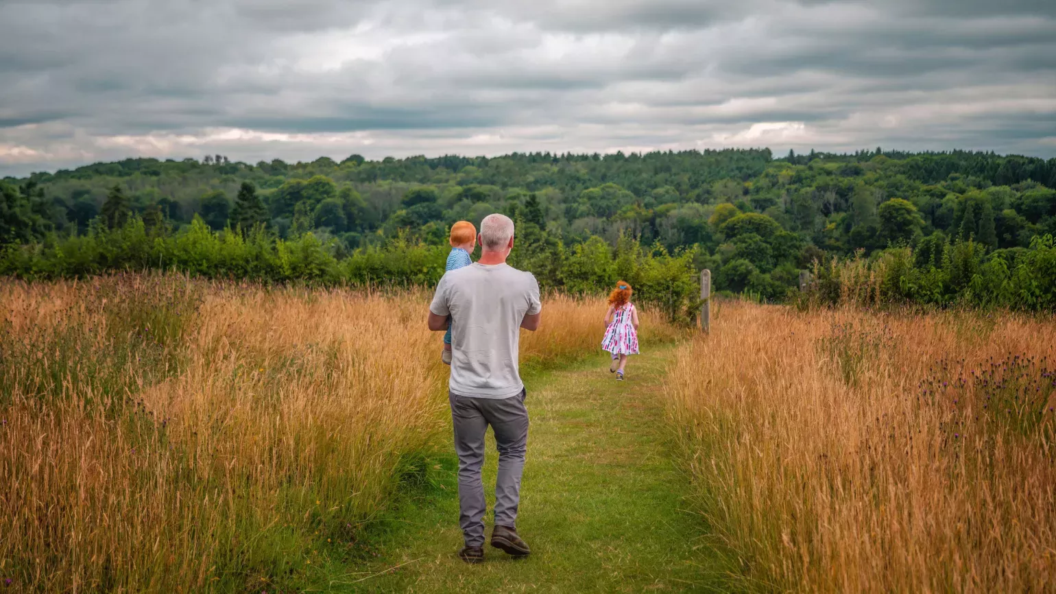 Father and two young daughters strolling through a meadow