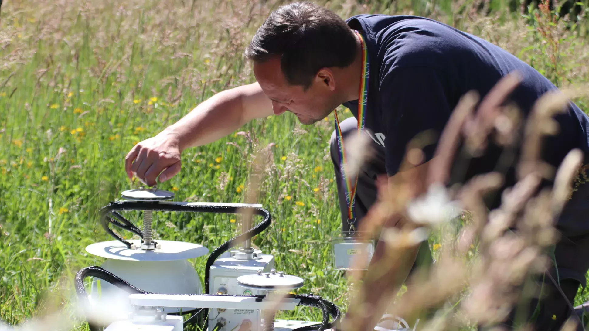 A person adjust pieces of white scientific equipment in a field of grass