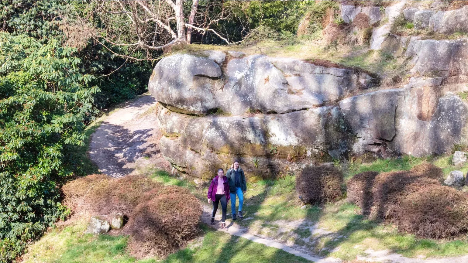 A pair of people walk through a rocky landscape