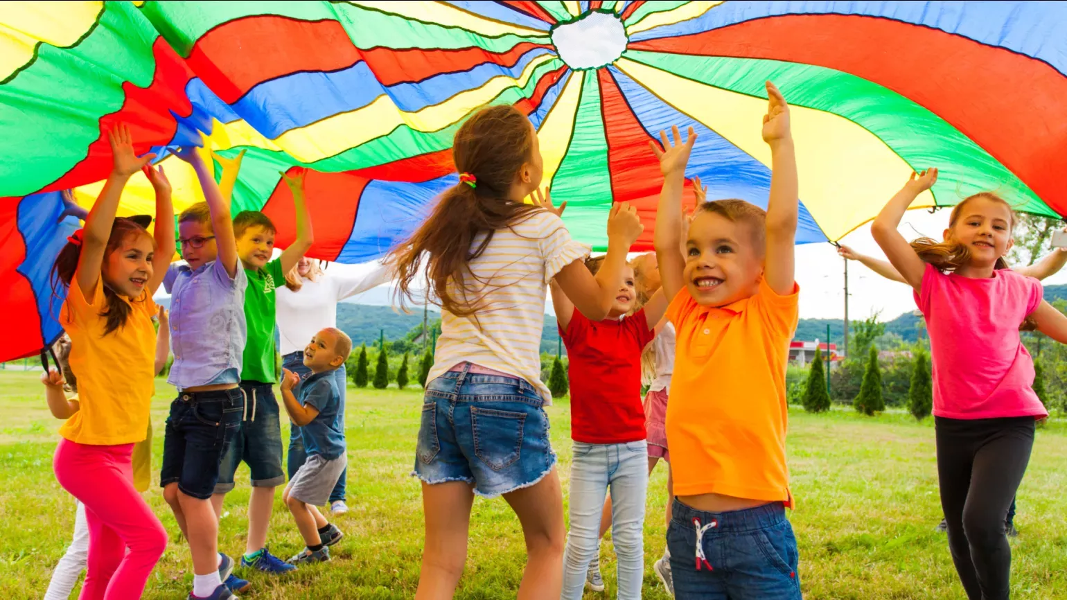 Children playing under a colourful parachute