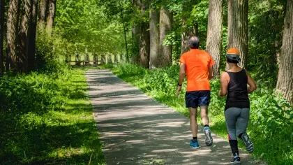 Two people running on a path in a woodland