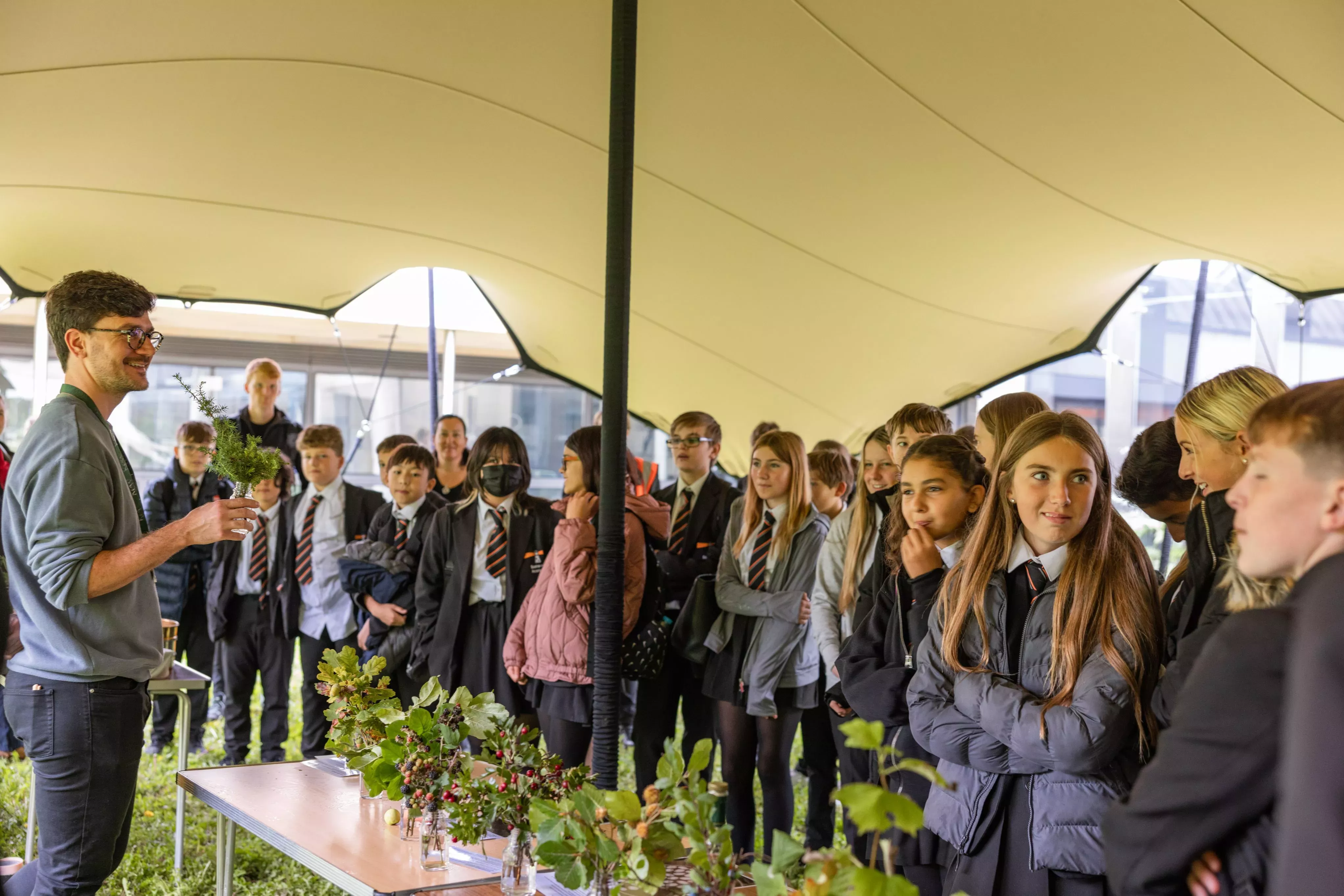 Group of students in a tent watching a young male teacher