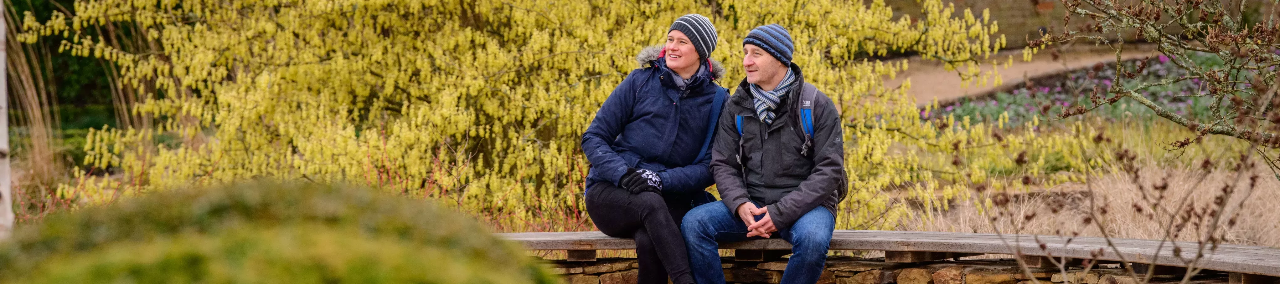 Two adults sat in Wakehurst gardens in winter