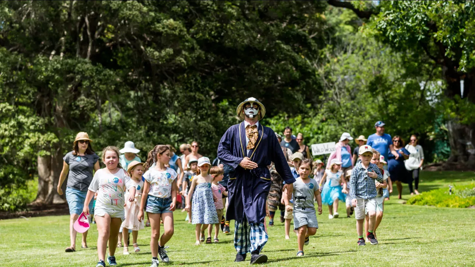 A man with a painted face leads a group of children through a field